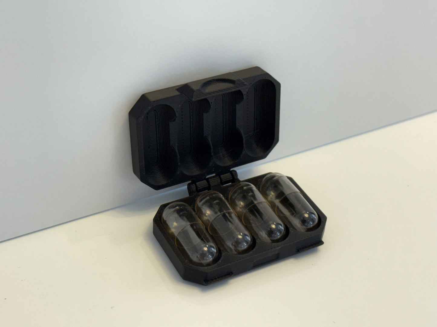 Capsule container with four (4) empty capsules inside
